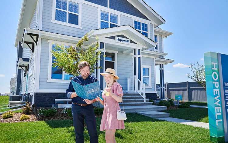 Young couple standing outside showhome reviewing brochure