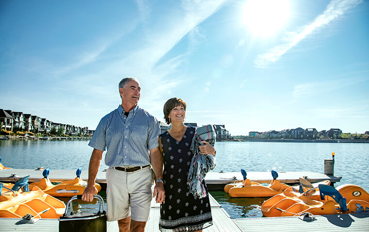 Older couple holding picnic basket walking on dock of Mahogany Lake