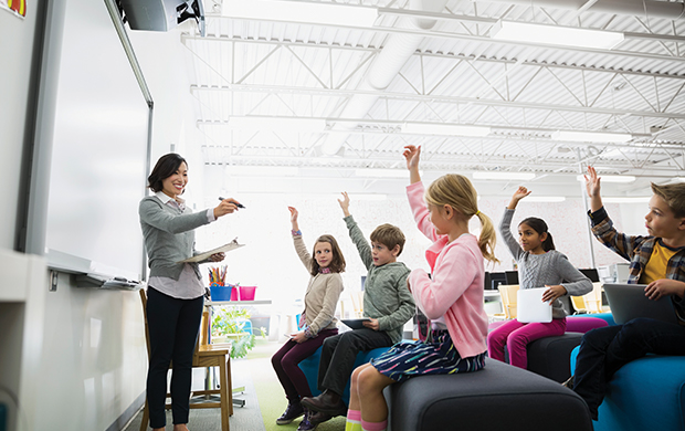 Kids raising their hands in classroom